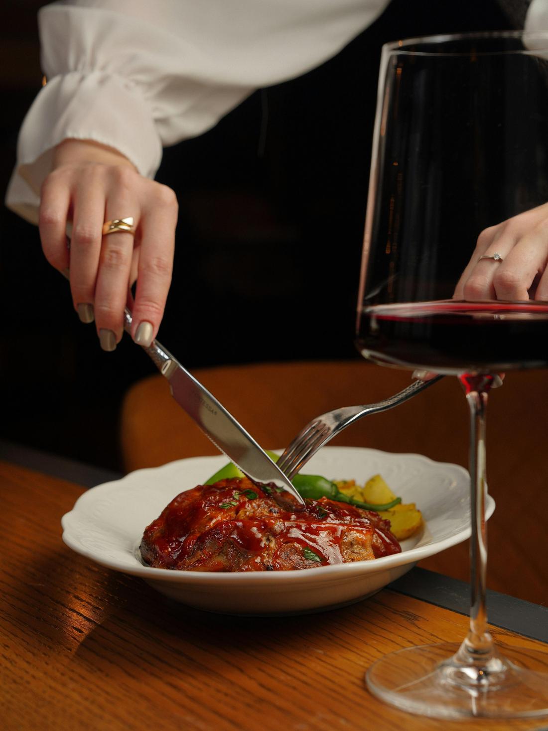 A plated dinner and a glass of red wine at a candlelit table